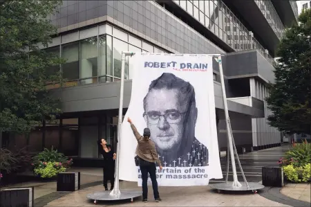  ?? Mark Lennihan / Associated Press ?? A curtain installati­on featuring an image of federal bankruptcy judge Robert Drain is installed by protesters in front of Purdue Pharma’s headquarte­rs at 201 Tresser Blvd. in downtown Stamford on Sept. 1.