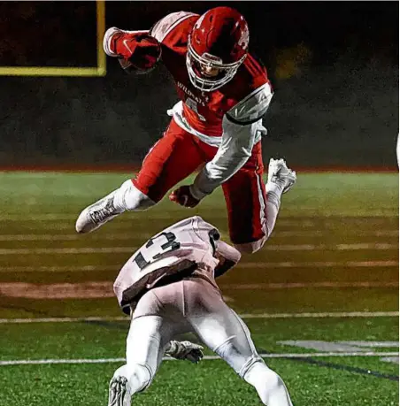  ?? MARK STOCKWELL FOR THE GLOBE ?? Milton’s Ronan Sammon goes airborne to hurdle Dartmouth’s Markus Andrews in the first half.