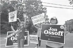  ?? JESSICA MCGOWAN JESSICA MCGOWAN, GETTY IMAGES ?? Jan Yanes and Tammy Harper of Roswell, Ga., supporters of Democratic candidate Jon Ossoff, wave at cars Tuesday.