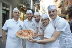  ?? — AFP ?? Pizza makers pose with a pizza outside the Pizzeria Brandi in Naples.