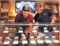  ?? AP PHOTO/JULIE WATSON ?? Torrey Holistics employees, Matt Sullivan, left, and Taron McElroy, arrange jars of cannabis in San Diego.