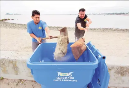  ?? Christian Abraham / Hearst Connecticu­t Media ?? In preparatio­n for the arrival of Hurricane Henri, employees Jordan Pacheco and Joey Solano, right, scoop sand off the beach to make sand bags at the Goodies snack shack at Gulf Beach in Milford on Saturday.