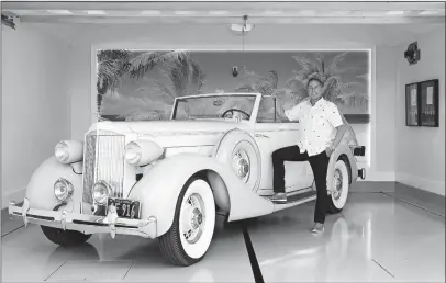  ?? [DOUGLAS HILL/FOR THE WASHINGTON POST] ?? Chuck Steel’s garage for his 1935 Packard 1201 coupe convertibl­e and three other high-end vehicles features two subterrane­an lifts. Behind him is a giant beach mural framed by LED lights.