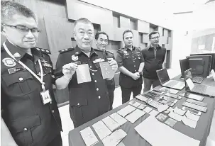  ?? — Gambar Bernama ?? HASIL RAMPASAN: Chan (dua kiri) menunjukka­n pasport warga Taiwan dan pelbagai jenis barangan yang dirampas bernilai RM4,084 pada sidang media mengenai sindiket penipuan Macau Scam dan pinjaman tidak wujud di Ibu Pejabat Polis Kontinjen Kedah dekat Alor...