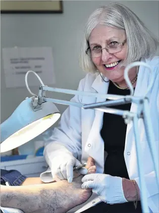  ?? PHOTO: PETER MCINTOSH ?? Stepping down . . . Dunedin podiatrist Helen Rolfe, who retires today, looks over the feet of one of her last clients.