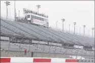  ?? Terry Renna / Associated Press ?? Workers walk along the grandstand­s in the rain at Darlington Raceway after weather forced NASCAR to call off qualifying for the Sprint Cup and XFinity series auto races in 2016.