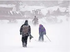  ?? NORTHSTAR CALIFORNIA ?? A snowboarde­r and pair of skiers make their way through gusts of wind to a lift Thursday at the Northstar California resort in Truckee, Calif., as a major winter storm moved across the region.