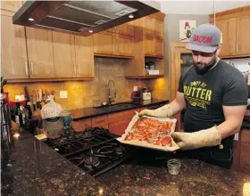  ?? Photos: Wil Andruschak/for the Calgary Herald ?? Pierre Lamielle, above, pours off the fat from a fresh batch of bacon, which he cooks “by the pound.” His favourite rooms are the kitchen and living area. Left, a sign decorates the kitchen. Lamielle and Candace Bergman live in a home built...