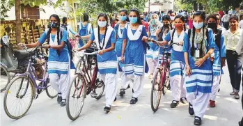  ?? PTI ?? Girls wearing face masks arrive at a school that was reopened as part of Unlock 5 after remaining closed for months due to coronaviru­s pandemic in Gorakhpur yesterday.