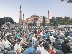  ??  ?? OPEN DOORS: People, some wearing face masks, pray outside the Hagia Sophia museum in Istanbul on Friday.