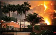  ?? AP PHOTO BY JAE C. HONG ?? A wildfire threatens homes as it burns along a hillside in La Conchita Thursday. The wind-swept blazes have forced tens of thousands of evacuation­s and destroyed dozens of homes.