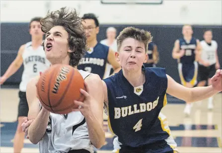  ?? JULIE JOCSAK
THE ST. CATHARINES STANDARD ?? Thomas Cryer of the Lakeshore Gators keeps the ball ahead of Brendan Barker of the Sir Winston Churchill Bulldogs in high school basketball.