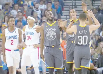  ??  ?? Golden State Warriors forward Draymond Green (third left) high fives guard Stephen Curry (right) with forward Kevin Durant (second right) during the first quarter against the LA Clippers at Oracle Arena. — USA TODAY Sports photo