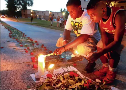  ?? Picture: AP ?? Theo Murphy, left, of Florissant, Missouri, and his brother, Jordan Marshall, 11, light candles at a memorial in Canfield Drive in Ferguson, where Michael Brown was shot dead by a policeman earlier this month. A small group of people laid roses along...