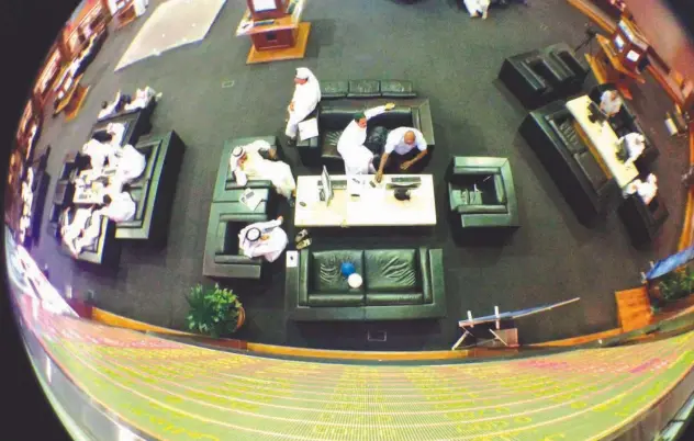  ?? Reuters ?? ↑
An electronic board displaying stock informatio­n is seen as investors work on the trading floor at the Dubai Financial Market.