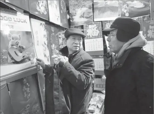  ?? PHOTOS BY WANG ZHUANGFEI / CHINA DAILY ?? Jin Anguang (right) talks with a customer at his calendar shop in Beijing.