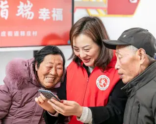  ??  ?? 江苏省海安市孙庄街道­韩庄村，志愿者在指导老年人使­用智能手机。图/CFP
