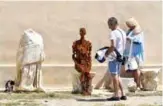  ??  ?? Tourists look at the steel statue called “Rule” created by renowned British artist Antony Gormley, during his exhibition “Sight”, as they walk past the museum at the archeologi­cal site of the island of Delos, a UNESCO World Heritage Site.