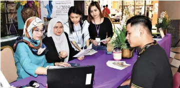  ??  ?? Hamidah (second left) and staff attend to students at the craft festival.