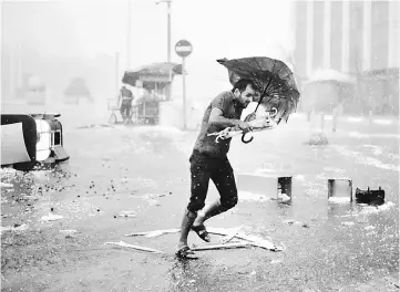  ??  ?? A man holds an umrella during a heavy downpour of hail at Taksim in Istanbul. — Reuters photo