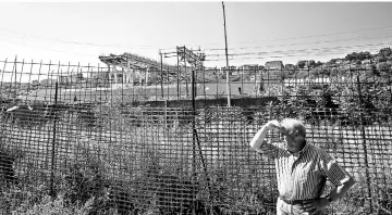  ??  ?? A man stands in front of the Morandi Bridge near the ‘red zone’ of via Fillak (Fillak road) in Genoa. — AFP photo