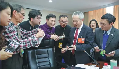  ?? KUANG LINHUA / CHINA DAILY ?? Journalist­s covering the annual two sessions add Sio Chi-wai, a member of the Macao Special Administra­tive Region’s delegation to the 13th National People’s Congress, to their mobile contact lists for further interviews at Beijing Hotel on Monday. The...