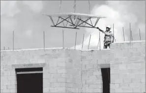  ?? AP/ LYNNE SLADKY ?? A constructi­on worker guides material into place in August at the Landmark community, a group of condos and townhouses built by Lennar Homes in Doral, Fla. The Commerce Department said U. S. constructi­on spending in July rose 0.7 percent to a...