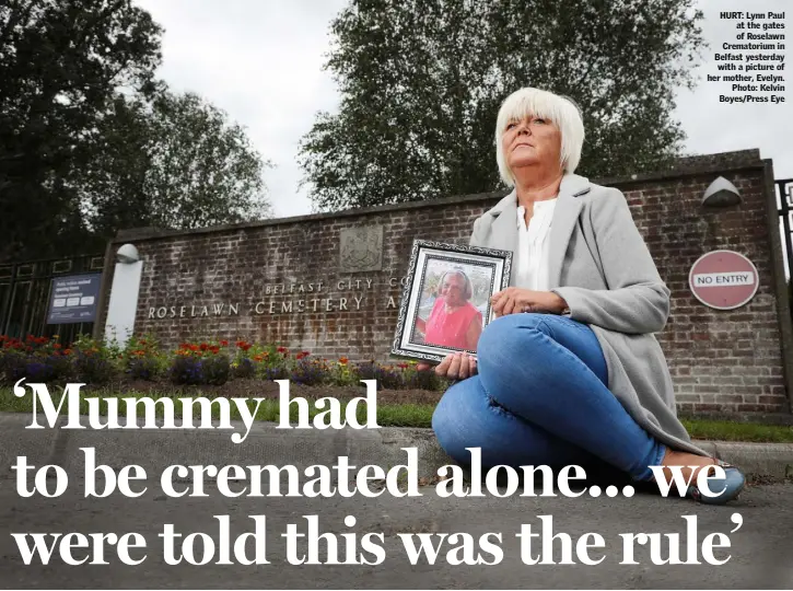  ??  ?? HURT: Lynn Paul at the gates of Roselawn Crematoriu­m in Belfast yesterday with a picture of her mother, Evelyn. Photo: Kelvin Boyes/Press Eye