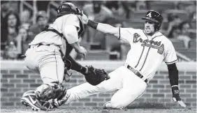  ?? THE ASSOCIATED PRESS ?? The Atlanta Braves’ Matt Adams, right, is tagged out at home by Seattle Mariners catcher Mike Zunino on Monday in Atlanta.