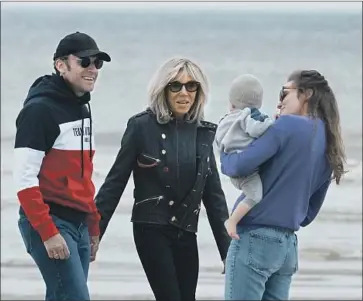  ?? Thibault Camus Associated Press ?? PRESIDENT Emmanuel Macron, with wife Brigitte Macron, greets supporters Saturday on a beach in northern France. If he wins Sunday’s election, he will become the first two-term president in 20 years.