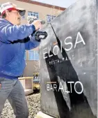  ??  ?? Drury Plaza Hotel employee Agustin Robledo Hinojosa puts the finishing touches on the Eloisa Restaurant sign on Palace Avenue.