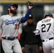  ?? DAVID ZALUBOWSKI — THE ASSOCIATED PRESS ?? Los Angeles Dodgers first baseman Scott Van Slyke, left, pulls in a pop fly off the bat of Colorado Rockies’Trevor Story in the first inning of a baseball game Friday, in Denver.