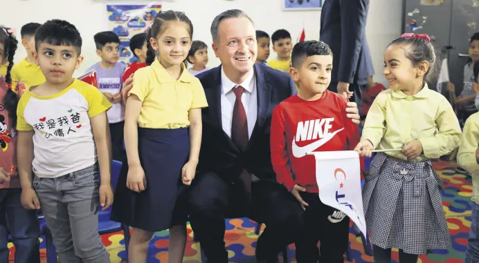  ?? ?? Turkish Cooperatio­n and Coordinati­on Agency (TİKA) President Serdar Kayalar poses with kids during the inaugurati­on of the Şakaik Kindergart­en renovated by TİKA, Baghdad, Iraq, April 2, 2024.