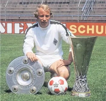  ??  ?? Erinnerung­en an große Gladbacher Zeiten: Berti Vogts mit Meistersch­ale und Uefa-Pokal.