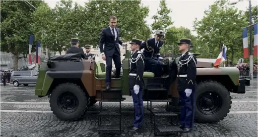  ??  ?? Premier déplacemen­t présidenti­el, sur les Champs-Elysées, à bord d’un command car de l’Armée de terre, le 14 mai.
