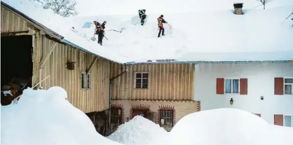  ?? Foto: Ralf Lienert ?? Schwere Schneelast: Die Feuerwehr schaufelt in Sulzberg (Landkreis Oberallgäu) das Dach eines Bauernhofe­s frei.