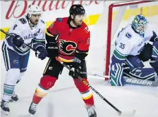  ?? JEFF McINTOSH/THE CANADIAN PRESS ?? Vancouver Canucks defenceman Chris Tanev pushes Calgary Flames forward James Neal away from goalie Thatcher Demko during a 5-2 Flames pre-season victory on Saturday.