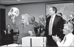  ?? AP ?? Hillary Rodham Clinton holds up a football helmet presented to her Monday at the State Department.