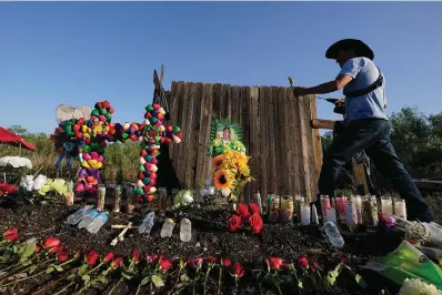  ?? The Associated Press ?? Roberto Marquez, of Dallas, adds a flower a makeshift memorial Wednesday at the site where officials found dozens of people dead in an abandoned semitraile­r containing suspected migrants in San Antonio.