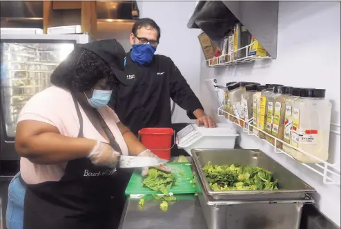  ?? Ned Gerard / Hearst Connecticu­t Media ?? Cassie, a student at Boys & Girls Village, works to prepare salads in the cafeteria on the village’s campus in Milford. She is seen here with life skills and vocational culinary instructor Bill Weitzler.