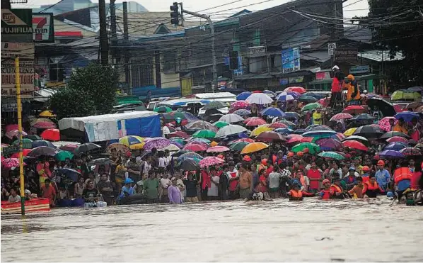  ??  ?? Anxious wait Residents wait for their family members being rescued at the end of a flooded street in the village of Tumana. Rains swamped the Philippine capital and nearby provinces forcing the government to close schools, public and private offices...