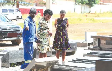  ?? — Pictures: Charles Muchakagar­a. ?? A stone mason shows prospectiv­e buyers some of the tombstones on sale on Bulawayo Road in Harare last week.