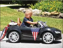  ?? MELANIE BELL / THE PALM BEACH POST ?? Ford Cryer, 2, is too little for a bicycle, so he drives in his car in the annual 4th of July Bike Parade led by the Tequesta Police Department at South View Park.