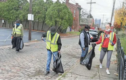  ?? BARBARA J. PERENIC/COLUMBUS DISPATCH ?? Volunteers, from left, Anthony Shanks, Larry Hergins, Ronald Tillman, Kim Hairston and Caroline Pyett, work to clean up Thurman Avenue in Columbus as part of the Cleaner Columbus effort.