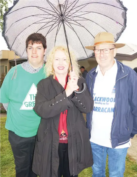  ?? Photograph: EMMA BALLINGALL ?? Rain didn’t dampen the spirits of candidates in the Narracan electorate on Saturday. Sheltering from the weather as they mixed with voters at the Warragul Community Pre-school voting booth are (from left) William Hornstra (Greens), Christine Maxfield (ALP) and Gary Blackwood (Liberal).