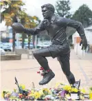  ?? Picture: Getty Images ?? A bronze statue of Sir Colin Meads is surrounded by tributes in Te Kuiti yesterday.