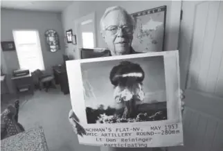  ?? Jeremy Papasso, Daily Camera ?? Donald Reininger, in his home in Louisville, holds a photograph of a 1953 nuclear test in Nevada in which he, as a second lieutenant, took part.