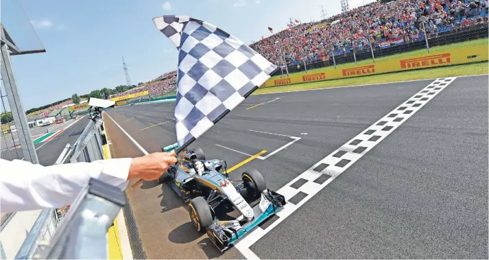  ??  ?? Lewis Hamilton recibe la bandera a cuadros en Hungarorin­g.