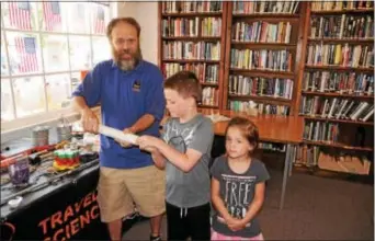  ??  ?? John Deininger, travelling science educator with The Franklin Institute, Philadelph­ia, shows Jackson Hughes, 7, of Marcus Hook, and his sister, McKinley, 4, how a corkscrew works. Deininger visited the Upper Chichester Library June 20 to kick off the...