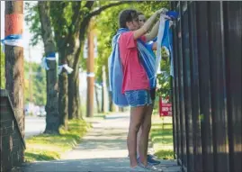  ?? The Associated Press ?? Volunteers tie ribbons on a fence Wednesday in preparatio­n for Otto Warmbier’ funeral in Wyoming, Ohio, today. Warmbier, a 22-year-old student, died after being detained for nearly a year and a half in North Korea.